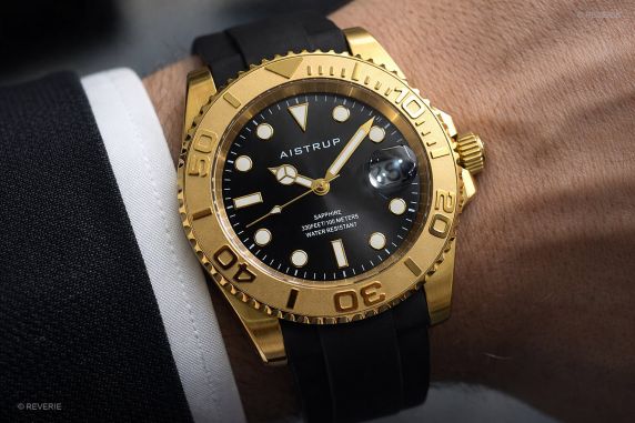 Aistrup sporttinen miesten kello mustalla kellotaululla, kultasävyinen kääntyvä kehä ja musta kumihihna | AIW8804